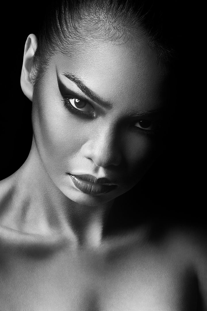 Black and white close-up with dramatic half-shadow lighting and intense direct gaze