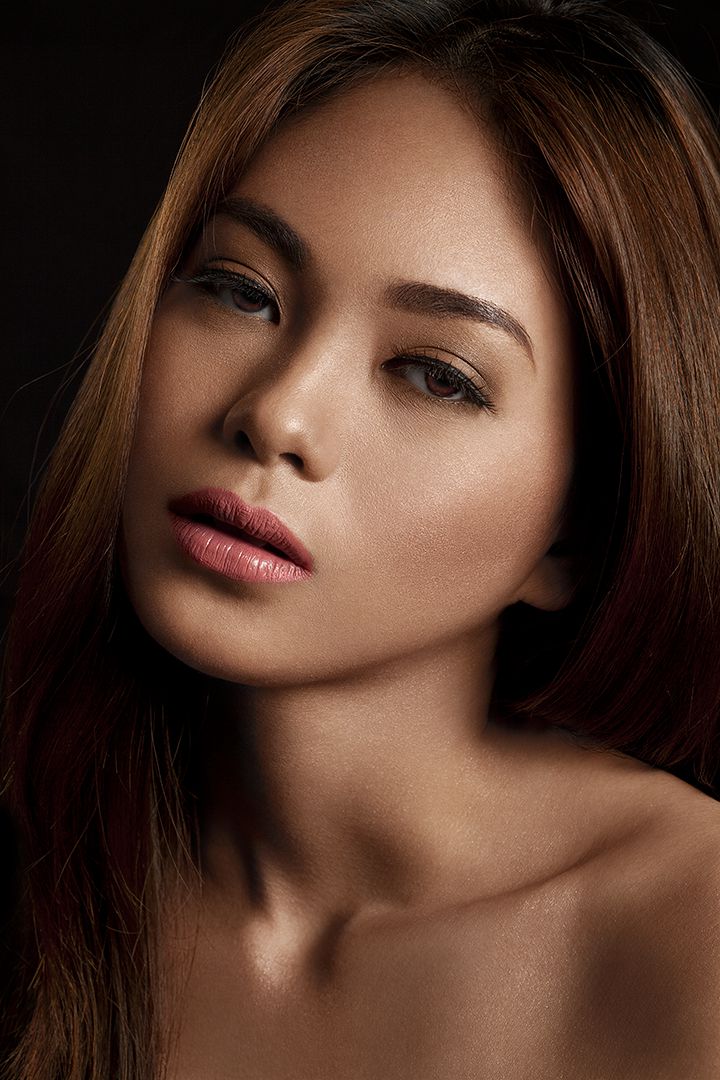 Low-key beauty portrait with natural glowing skin, rose-pink lips, and warm side lighting